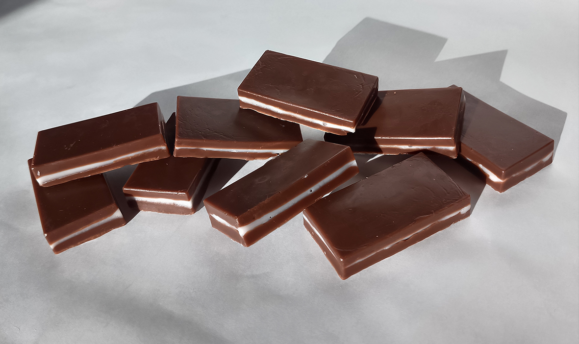 Bombones de jabón marrones con una capa rosa de fresa de base de jabón colocados sobre un fondo blanco.